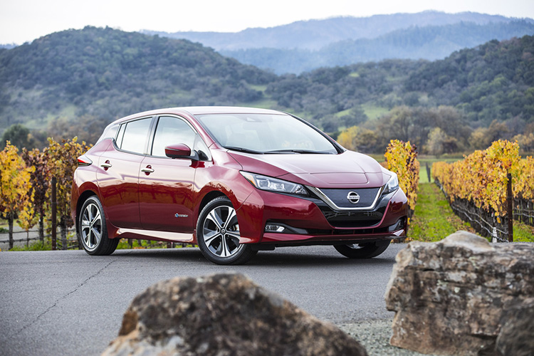A red Nissan LEAF parked on a hill