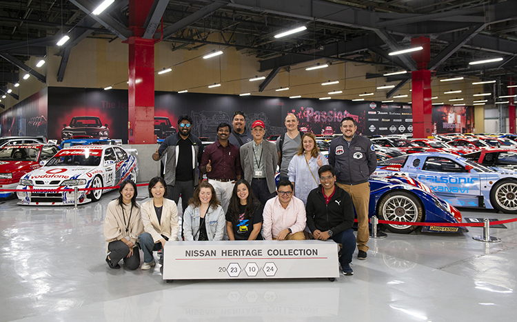 Personnes posant derrière une pancarte Nissan Heritage Collection