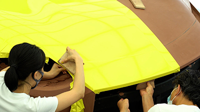 covering the hood of the clay car with a yellow colored wrap