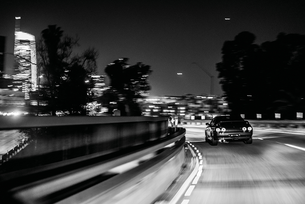 Black and white photo of a Nissan Skyline driving away