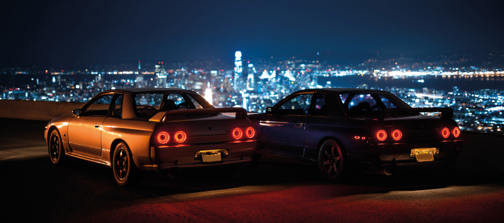 Two GT-Rs parked overlooking the night skyline of LA