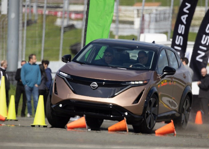 A brown Nissan EV skillfully navigates around cones.