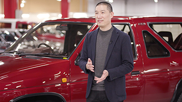 ken lee in front of a red nissan suv